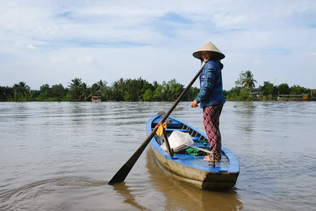 Barca en el Delta del Mekong Mujer con sombrero cónico remando en barca por el Delta del Mekong